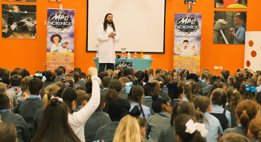 Mad Science instructor in front of group of school kids performing a mad science experiment 