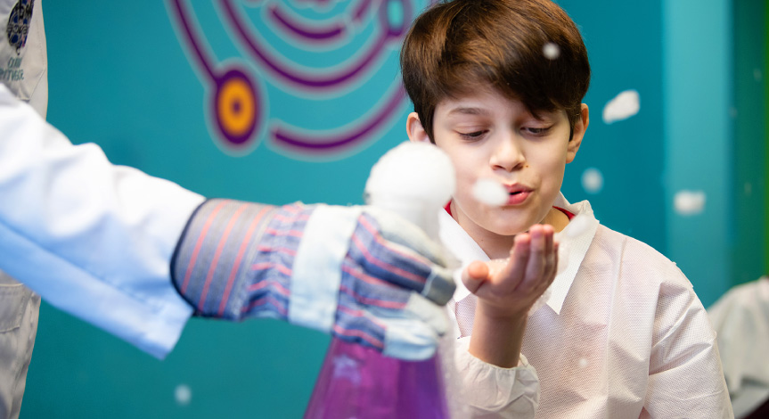 Boy blowing soap bubbles at a birthday party, after a dry ice experiment.
