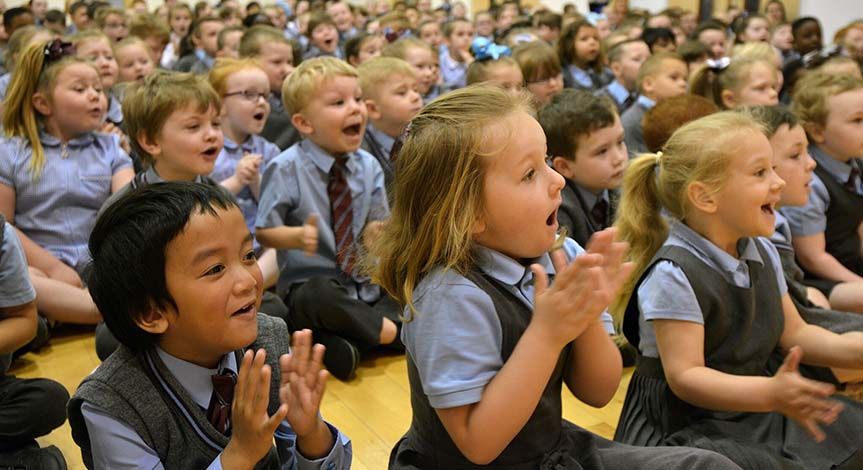 Kids at assembly sitting on the floor clapping